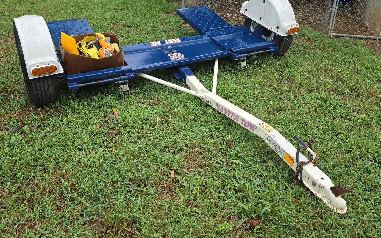 White Master Tow car dolly with navy ramps, hitched to a pickup